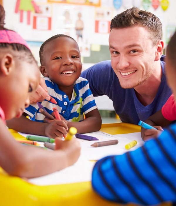 Volunteer teacher helping a class of preschool kids drawing